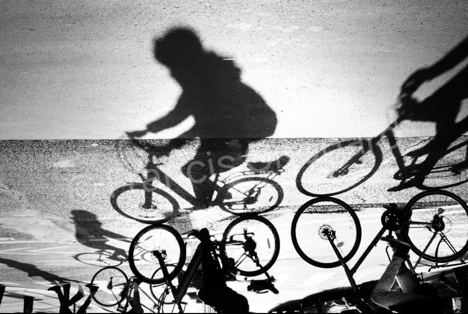 Ombre d’un cycliste sur le sol à travers une rampe en fer forgé, en noir et blanc