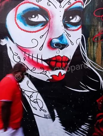 Un passant devant un grand visage peint aux couleurs vives, photographie de scène urbaine