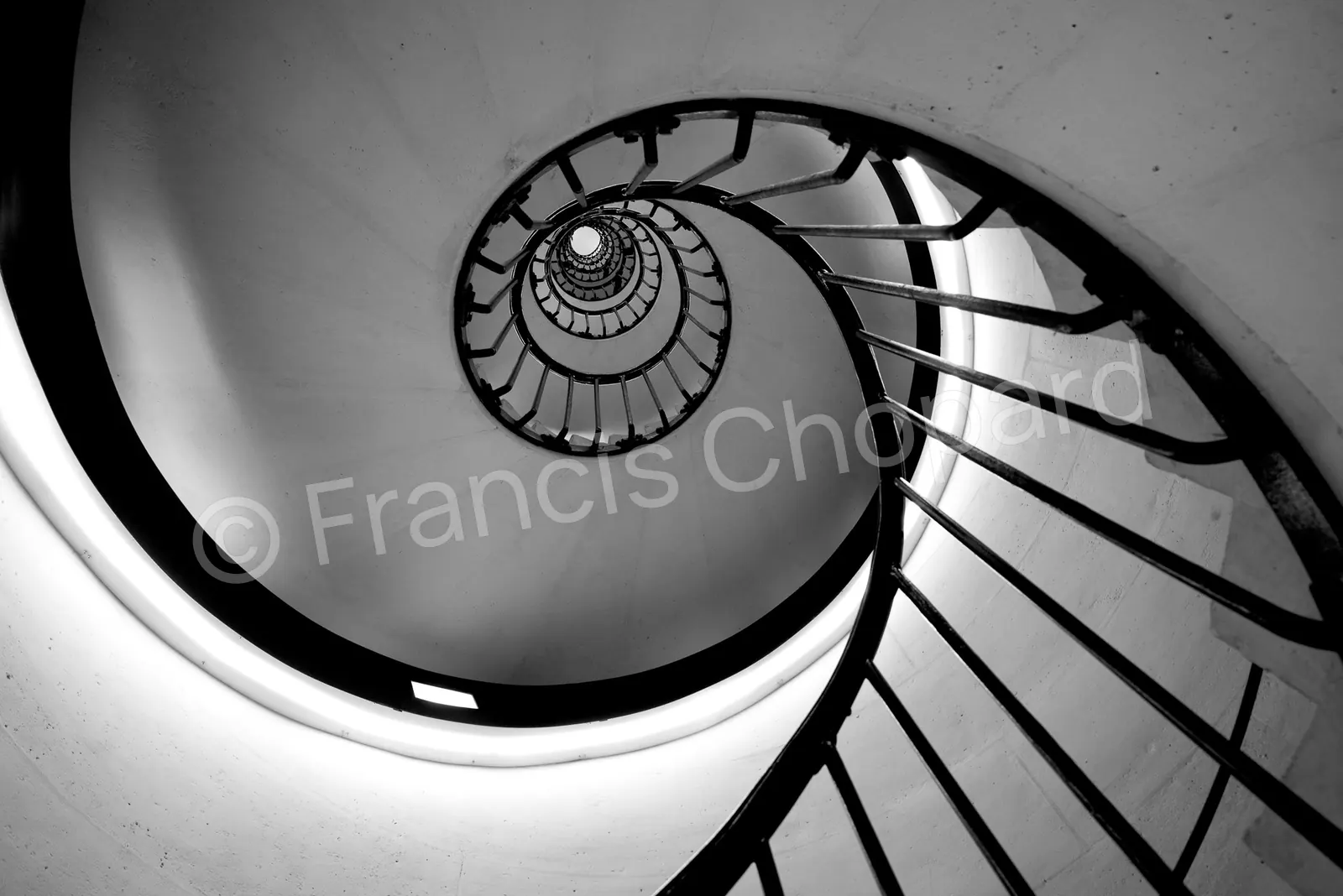 Spirale d’un escalier blanc et rampe noire