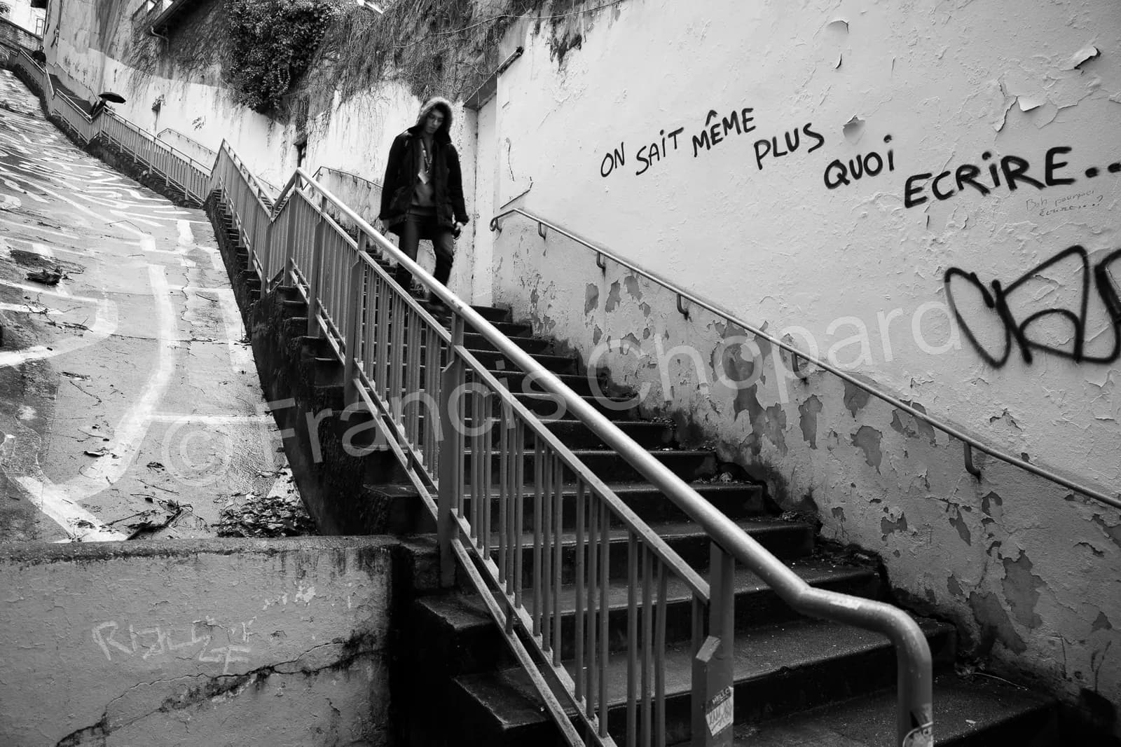 Un passant descend un escalier bordé de graffitis